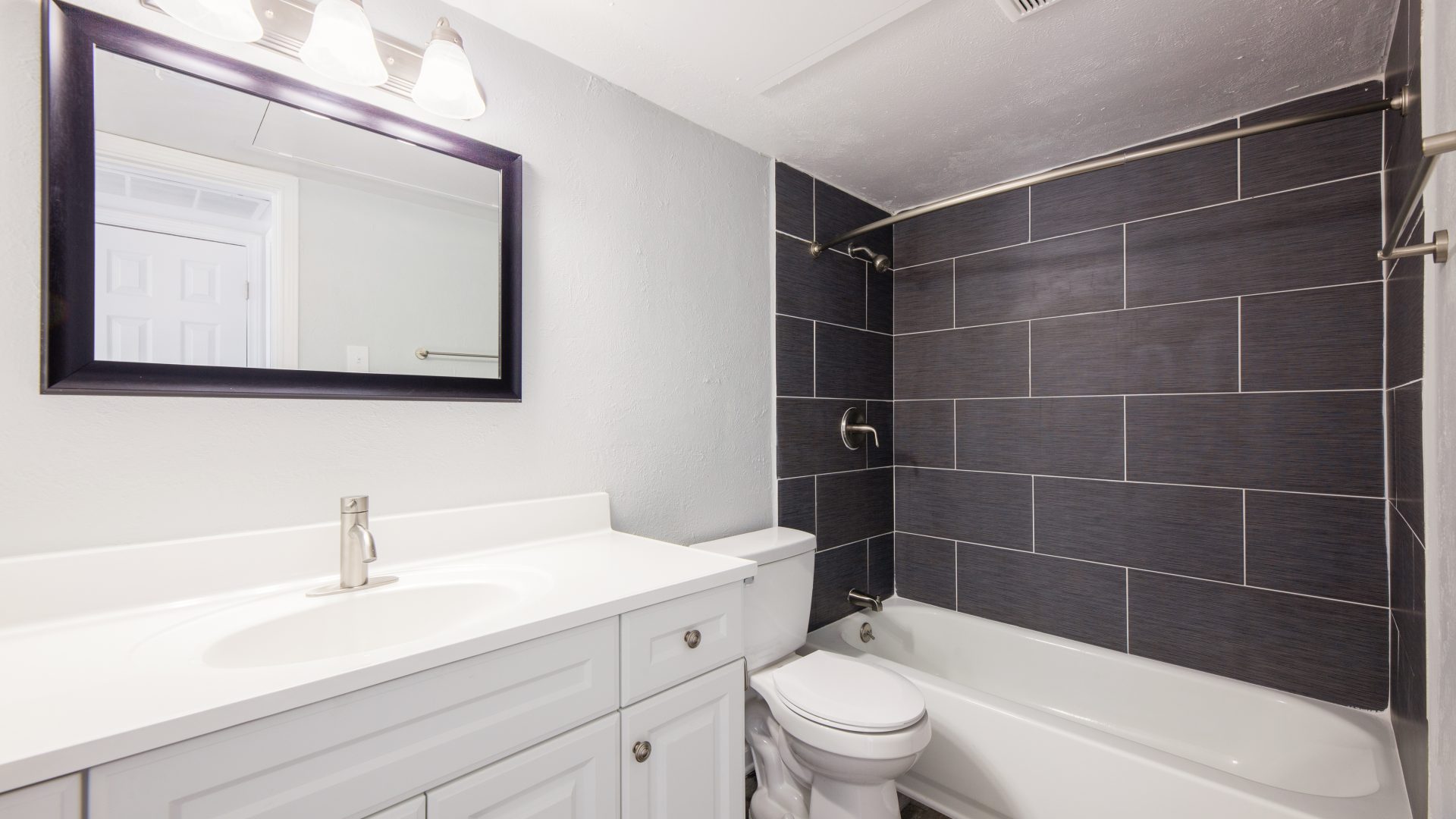 bathroom white vanity grey tile tub surround