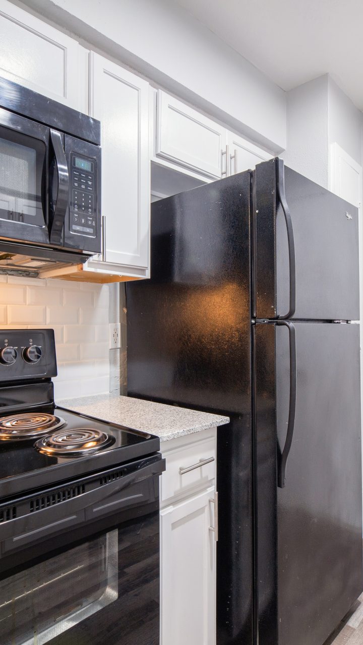 kitchen with black stove micro fridge white cabinets